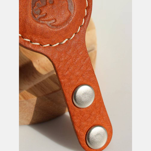 Close-up view of the front side of a brown Leather Airtag Chain, showcasing its intricate details, along with a focus on the button attachment