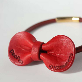 Close-up detail of a red Leather Removable Pet Bowtie with embossed name and phone number.